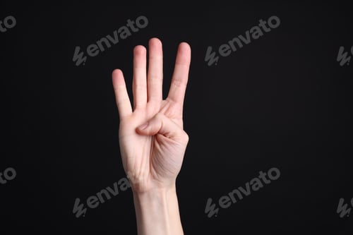 Preview: Woman showing number four with fingers on black background, closeup
