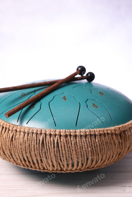 Preview: Steel tongue drum and mallets on light wooden table, closeup