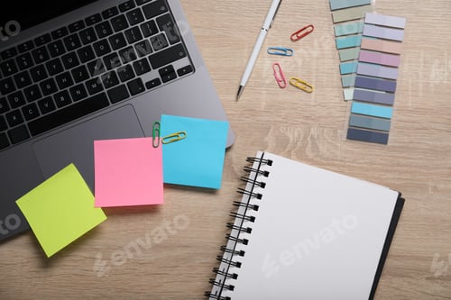 Preview: Laptop with colorful sticky notes and stationery on wooden table, flat lay. Multitasking and deadlin