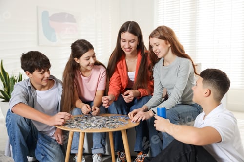 Preview: Group of teenagers solving puzzle together at home