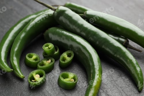Preview: Fresh chili peppers on black textured table, closeup. Whole and sliced