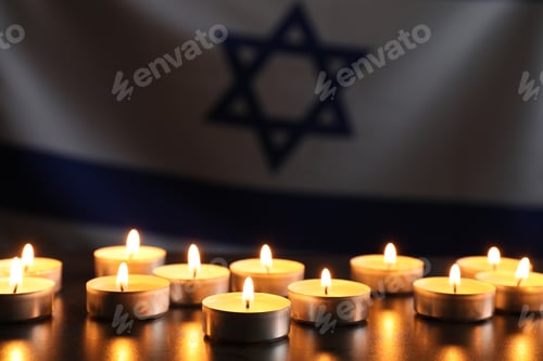Preview: Holocaust Remembrance Day. Burning candles on dark table against flag of Israel, closeup