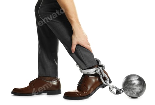 Preview: Businessman with metal ball and chain on his leg against white background, closeup