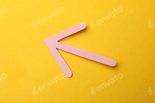 Preview: Pink paper arrow on yellow background, top view