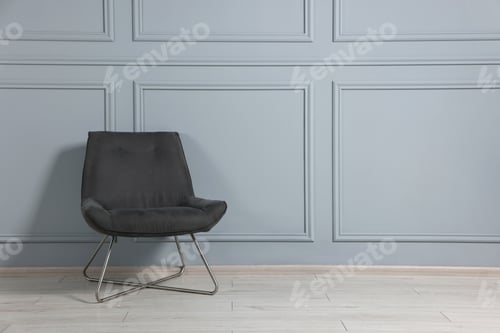 Preview: Comfortable armchair near grey wall in room, space for text