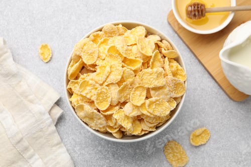 Preview: Tasty corn flakes in bowl, milk and honey on light grey background, flat lay