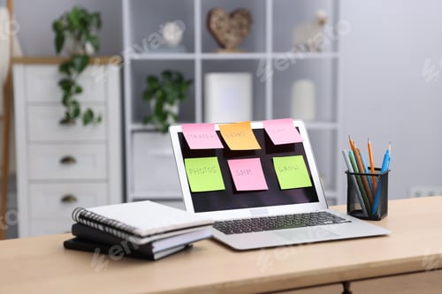 Preview: Laptop with colorful sticky notes and stationery on table indoors. Multitasking, deadline and rush a