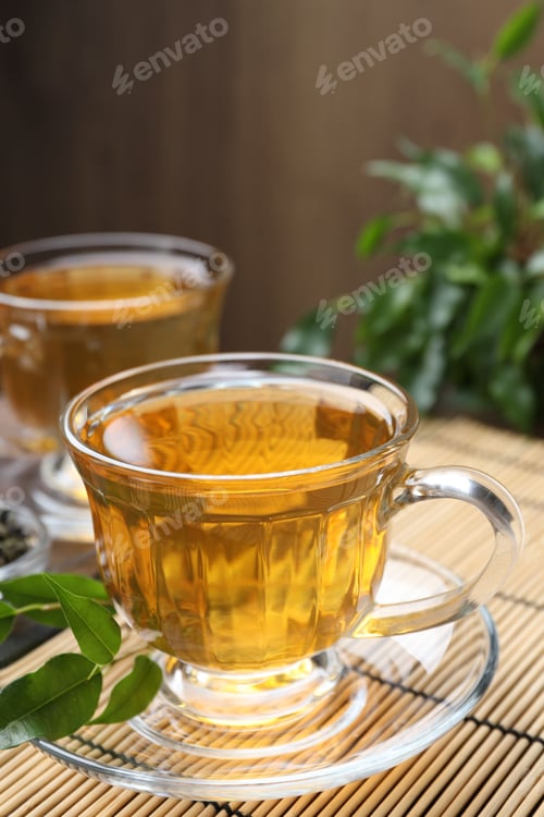 Preview: Refreshing green tea and leaves on wooden table, closeup