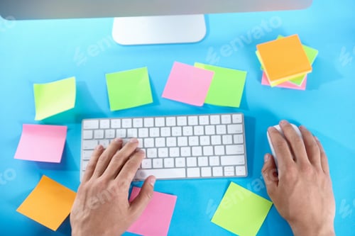 Preview: Man working at light blue table with blank sticky notes, top view. Multitasking, deadline and rush a