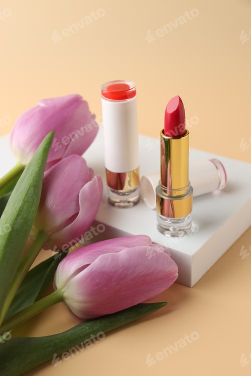 Preview: Lipsticks and flowers on beige background, closeup