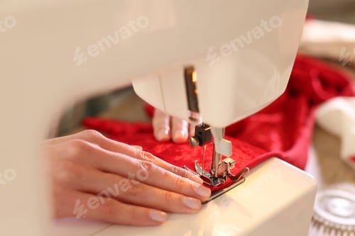 Preview: Woman sewing fabric with professional machine in workshop, closeup