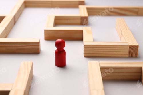 Preview: Maze made of wooden blocks and human figure on white background, closeup. Business strategy