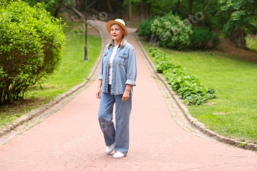Preview: Beautiful senior woman with straw hat walking in spring park