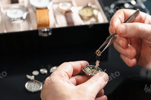Preview: Senior man fixing mechanism of vintage wrist watch at table indoors, closeup