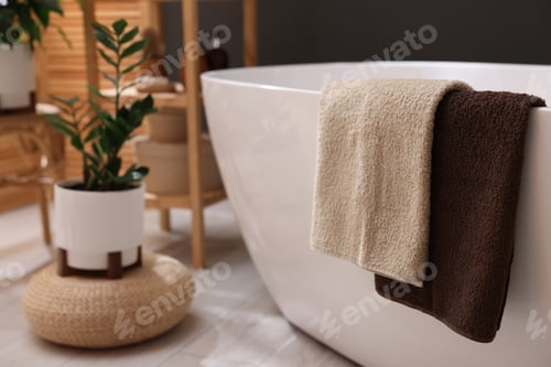 Preview: Bathtub with towels and green houseplants in bathroom, closeup