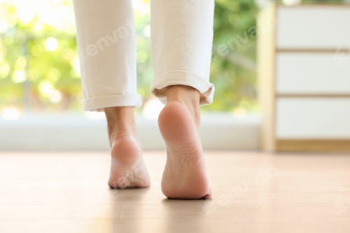 Preview: Woman walking barefoot on warm floor indoors, closeup. Underfloor heating