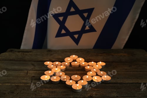 Preview: Holocaust Remembrance Day. Burning candles in shape of Star of David on wooden table and flag of Isr