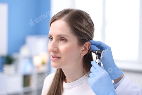 Preview: Hearing test. Doctor examining woman's ear with otoscope in clinic, closeup