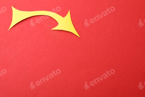 Preview: Yellow paper arrow on red background, top view. Space for text