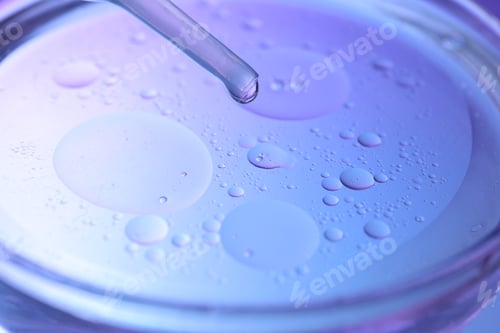 Preview: Dripping liquid from pipette into Petri dish on color background, closeup