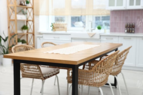 Preview: Blurred view of dining table with chairs in kitchen, closeup. Stylish interior