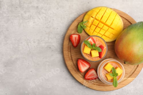 Preview: Delicious mango panna cotta, fruits and mint on grey table, top view. Space for text