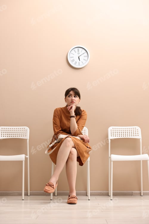 Preview: Woman sitting on chair and waiting for appointment indoors