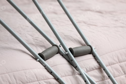 Preview: Metal axillary crutches near bed indoors, closeup. Mobility aid