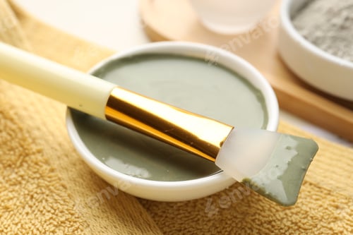 Preview: Clay mask, brush and towel on beige background, closeup