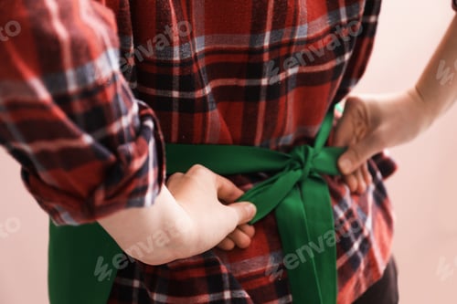 Preview: Woman tying clean apron on pink background, closeup