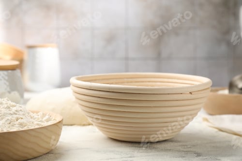 Preview: Sourdough proofing basket and flour on white marble table, closeup
