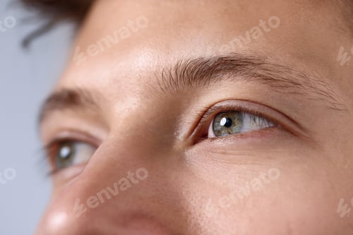 Preview: Young man with beautiful eyes on light grey background, closeup