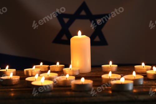 Preview: Holocaust Remembrance Day. Burning candles on table against flag of Israel, closeup