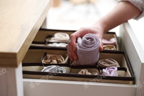Preview: Woman putting socks into drawer with organizer indoors, closeup