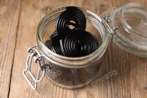 Preview: Natural licorice candies in jar on wooden table, closeup