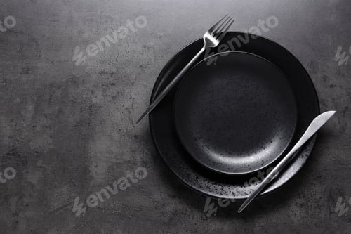 Preview: Black plates with cutlery on table, top view. Space for text