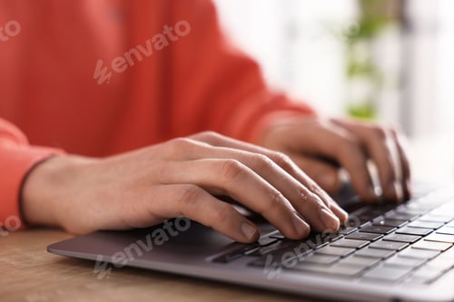 Preview: Woman working on laptop at wooden desk, closeup