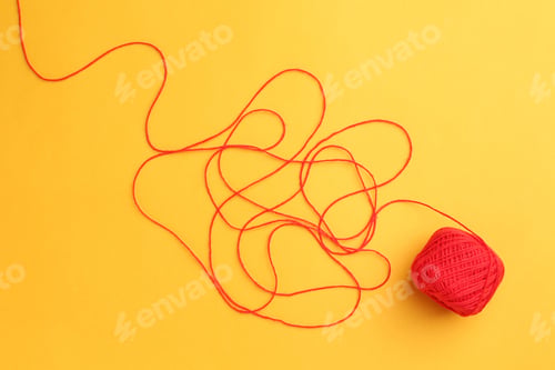 Preview: Ball of red yarn on yellow background, top view