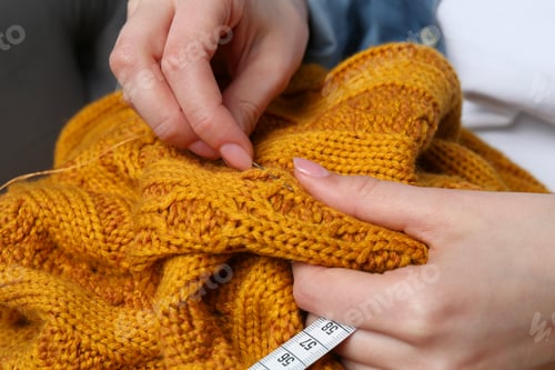 Preview: Woman sewing sweater with needle, closeup view
