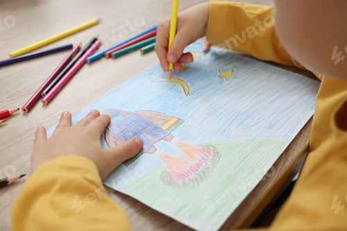 Preview: Little boy drawing with pencil at wooden table, closeup