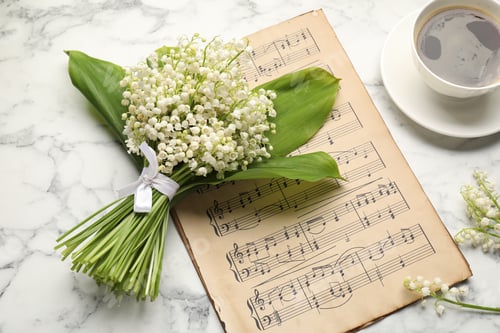 Preview: Beautiful lily-of-the-valley flowers, coffee and note sheet on white marble table