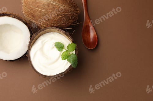 Preview: Tasty coconut yogurt with melissa in shell and nuts on brown background, flat lay. Space for text