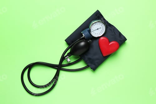 Preview: Measuring blood pressure. Sphygmomanometer and heart figure on light green background, top view