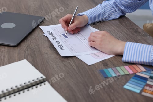 Preview: Woman with weekly planner at wooden desk, closeup