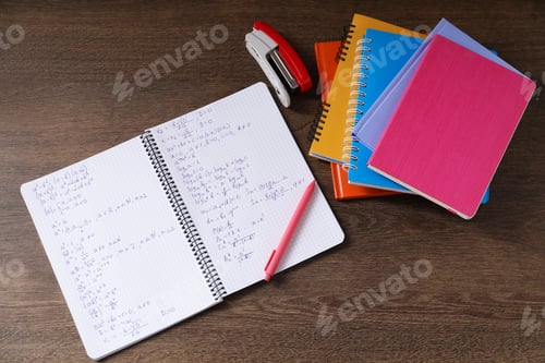 Preview: Homework. Notebook with math formulas and different stationery on wooden table, flat lay
