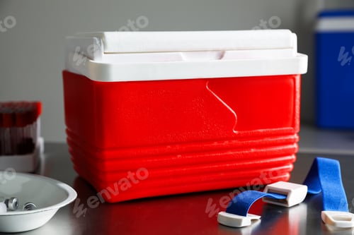 Preview: Cool box with ice cubes, test tubes of blood samples, vials and medical tourniquet on table in clini
