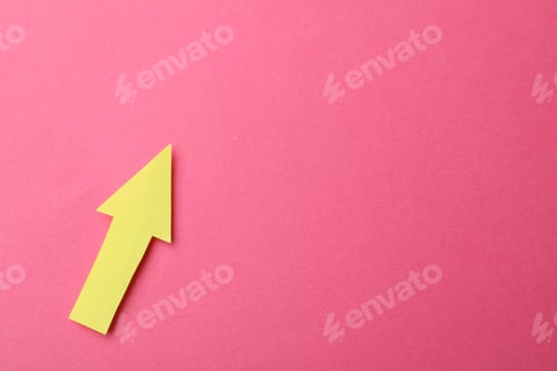 Preview: Yellow paper arrow on pink background, top view. Space for text