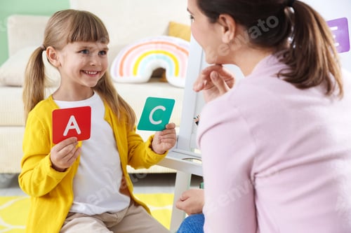 Preview: Mother teaching her daughter alphabet with letter cards at home, closeup