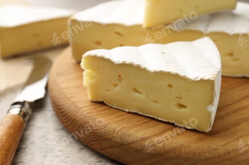 Preview: Cut delicious brie cheese and knife on grey table, closeup