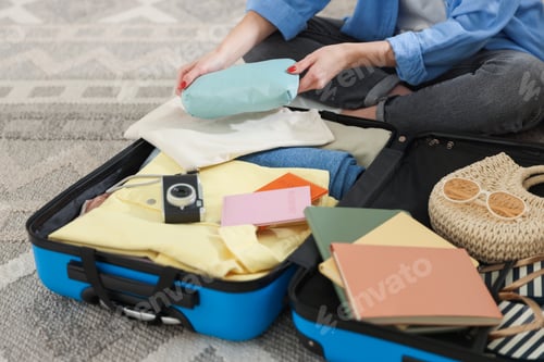Preview: Woman packing her belongings into suitcase on floor, closeup